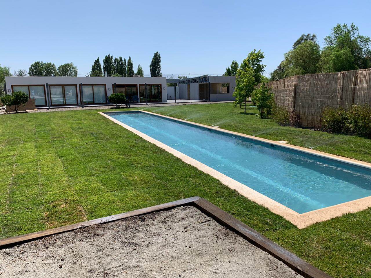 Jardín con piscina y pasto instalado